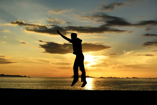 Silueta de hombre saltando en la playa — Foto de Stock