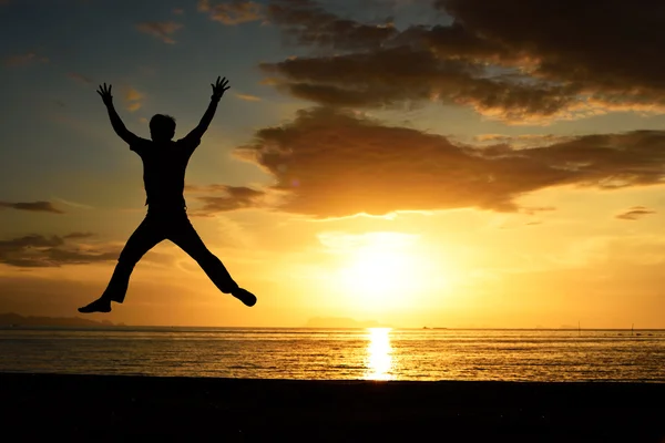 Silhouette of jumping man on beach — Stock Photo, Image