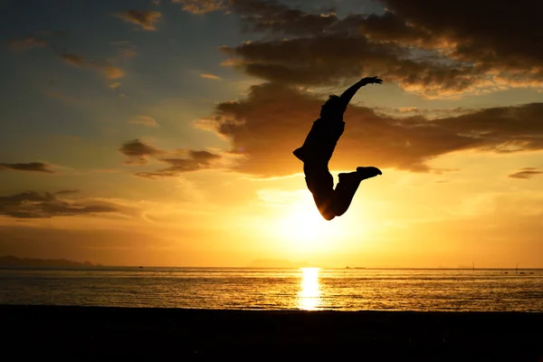 Silhouette of jumping man on beach — Stock Photo, Image