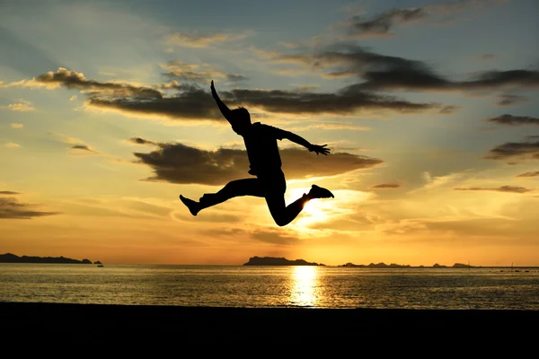 Silueta de hombre saltando en la playa — Foto de Stock