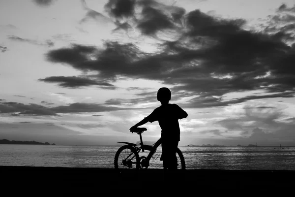 Силуэт мальчика с велосипедом на пляже — стоковое фото