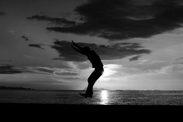 Silueta de hombre saltando en la playa — Foto de Stock