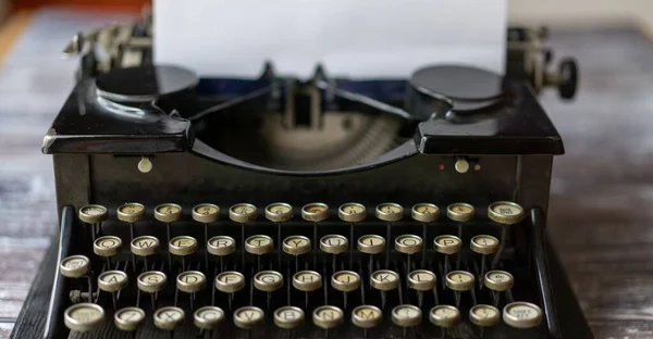 Close up of a vintage typewriter. Old vintage typewriter, retro machine with white sheet of paper and typed text. An extreme close up of the keys of a vintage typewriter on a dark background