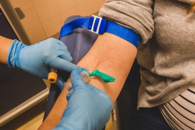 Hemşire bir hastadan kan alıyor. Coronavirus covid-19 kan enfeksiyonu. Damardan kan testi. Doppler ve kan testi hastanede. Doktor iğneyi doldururken tutuyor. Hemşire örnek alıyor..