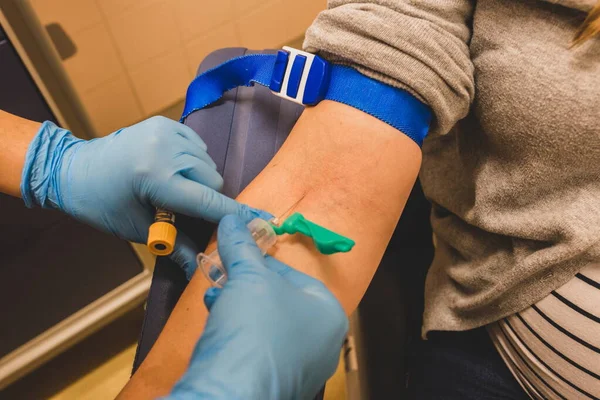 Hemşire bir hastadan kan alıyor. Coronavirus covid-19 kan enfeksiyonu. Damardan kan testi. Doppler ve kan testi hastanede. Doktor iğneyi doldururken tutuyor. Hemşire örnek alıyor..