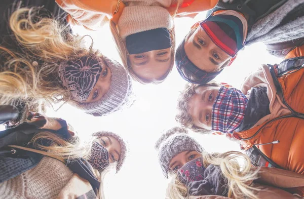 Diverse people wearing mask and taking a selfie - New normal concept with friends. Happy friends fun - New normal lifestyle concept. Teambuilding concept - Group of millennial generation friends looking down on camera. Young students teamwork.