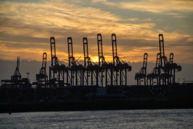 Hamburg Limanı, Almanya: bulutlu bir günde gün batımında vinç siluetleri