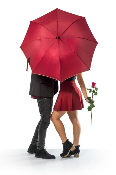 Casal atrás de um guarda-chuva vermelho — Fotografia de Stock