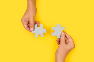 Sarı arka planda yapboz parçaları tutan kadın elleri