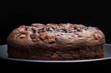 Koyu arkaplanda gri bir tabakta çikolatalı pasta.