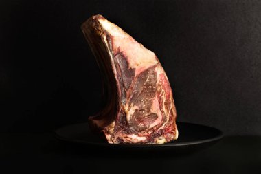 Siyah bir tabakta ve arka planda olgun bir biftek.