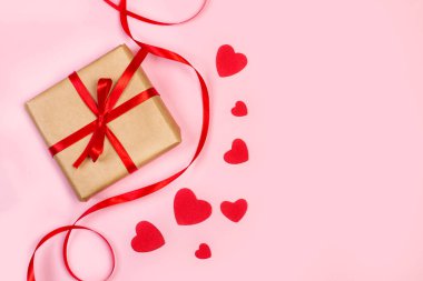Pembe arka planda kağıt kırmızı kalpler olan bir aziz sevgililer günü hediyesi.