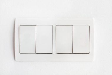 Beyaz bir duvarda dört beyaz ışık düğmesi var.