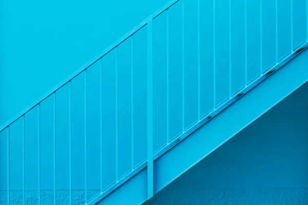 Metal blue staircase with blue railing on a blue wall