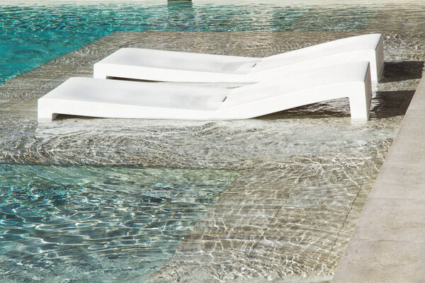 Two plastic deck chairs in a swimming pool