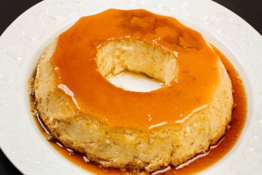 Beyaz seramik tabakta yumurtalı tart, siyah arka planda, en üstte.