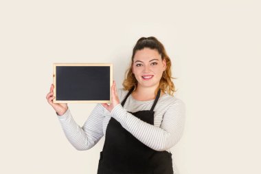 Siyah önlüklü kıvrımlı bir kadın elinde küçük boş bir tahta tutuyor.