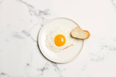 Beyaz bir tabakta yumurta, mermer bir masanın üstünde.