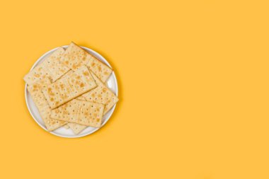 Beyaz tabakta kraker bisküvileri ve kopyalama alanı olan sarı bir arka planda