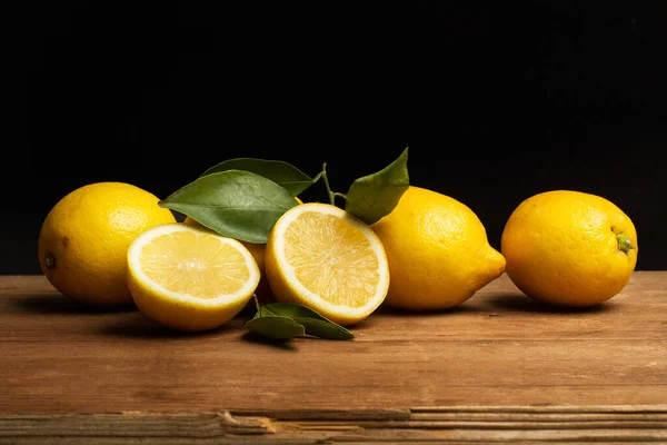Tahta bir masada ve siyah bir arka planda limonlar