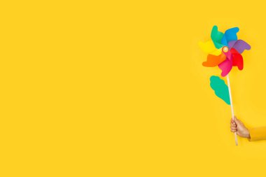 Sarı bir zemin üzerinde büyük bir fırıldak tutan kadının elinde kopya alanı var.