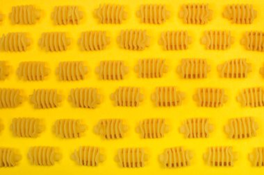 Sarı arkaplanda kuru radyatör makarnası.