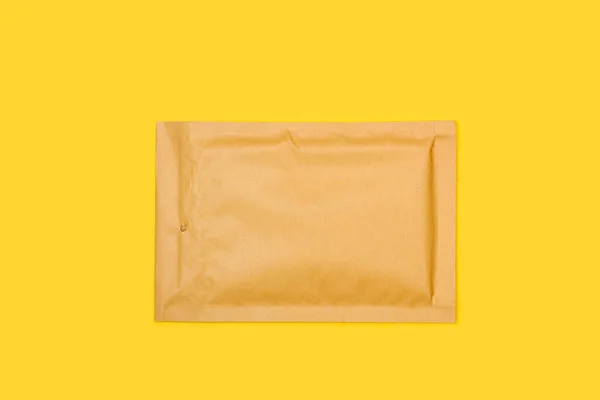 黄色の背景に茶色のパッド入り封筒 — ストック写真