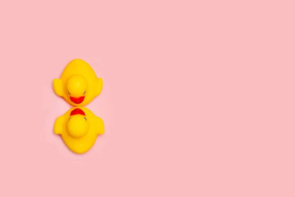 两个黄色橡胶玩具鸭面对着粉色背景的顶部视图 — 图库照片