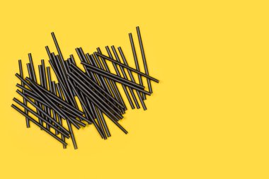 Fotokopi alanı olan sarı bir zemin üzerinde bir sürü siyah plastik pipet