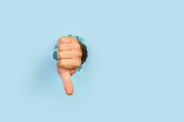 El ve baş parmağı açık mavi arkaplanda bir delikten aşağı hareket