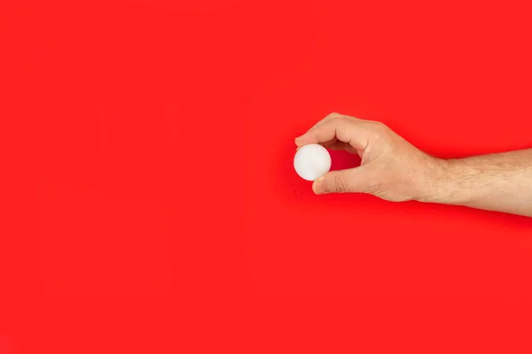 Männerhand Hält Einen Tischtennisball Auf Rotem Hintergrund — Stockfoto