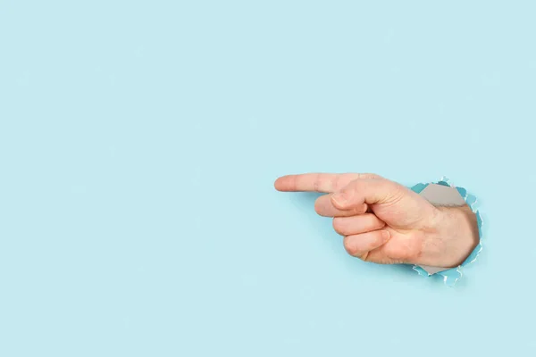 Człowiek Ręka Palcem Wskazującym Lewo Przez Dziurę Jasnoniebieskim Tle — Zdjęcie stockowe