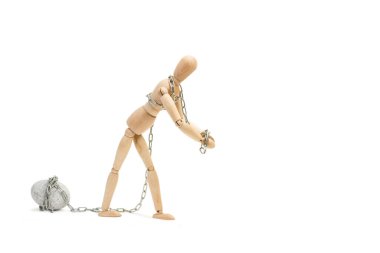 Beyaz arka planda zincirli bir taşı sürükleyen tahta bir manken oyuncağı.