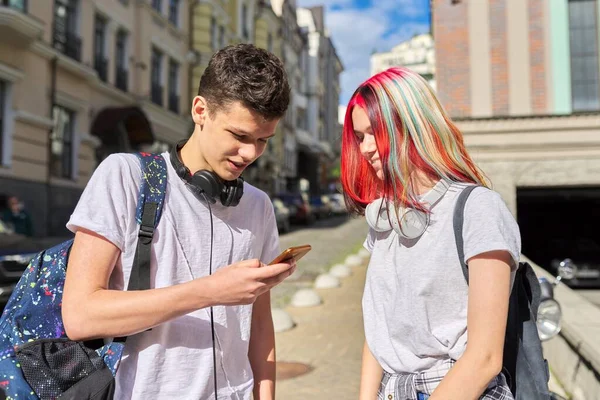 Подростки студенты парень и девушка с рюкзаками смотреть в смартфон — стоковое фото