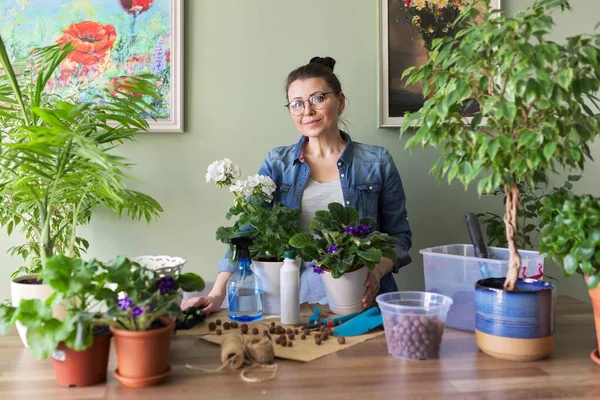 Vrouw die zorgt voor potplanten, herbeplanting, bemesting. — Stockfoto