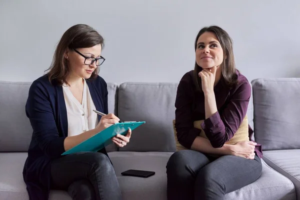 Social worker, psychologist talking to young woman in office.