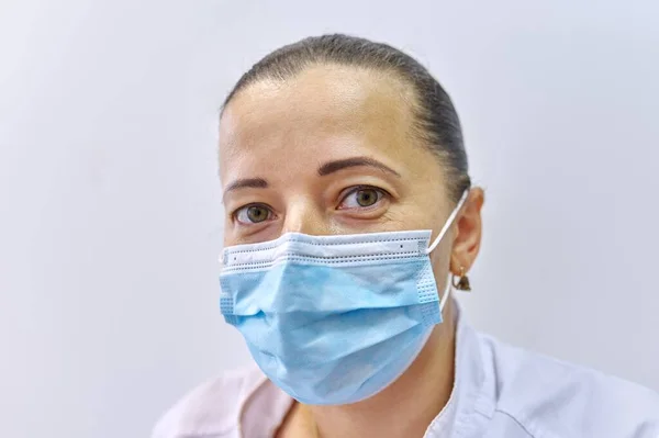 De cerca la cabeza de la mujer cansada médico en la máscara, mujer madura mirando a la cámara — Foto de Stock