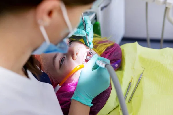 Dentista femenina tratando dientes a paciente, mujer joven en silla en clínica dental — Foto de Stock