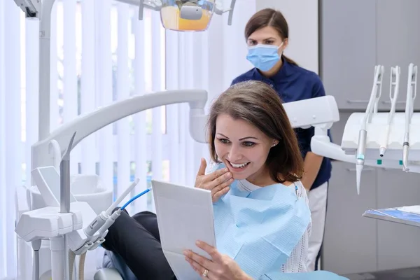 Gelukkige vrouw van middelbare leeftijd met dokter tandarts kijken in spiegel naar tanden — Stockfoto