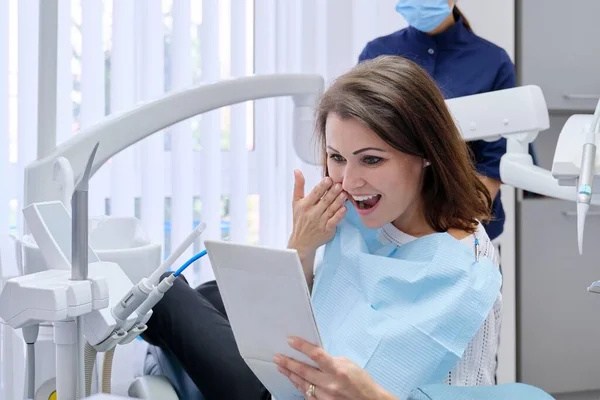 Szczęśliwa kobieta w średnim wieku z lekarzem dentystą patrzącym w lustro na zęby — Zdjęcie stockowe
