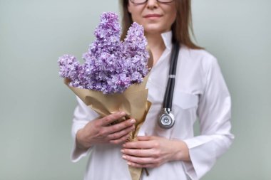 Kadın doktorun ellerinde bir demet leylak çiçeği.