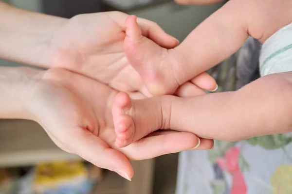 Yeni doğmuş bebek ayakları annelerin ellerinde. — Stok fotoğraf