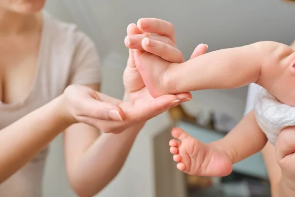 Nyfödda bebisfötter i mammas händer — Stockfoto