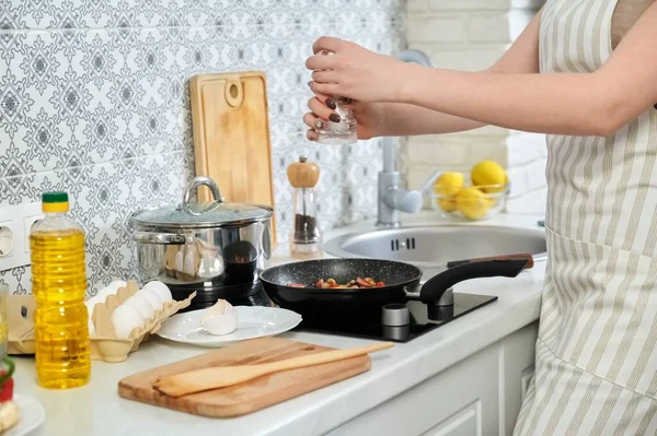 Giovane bella donna che cucina a casa in cucina, fritture uova con salsicce — Foto Stock