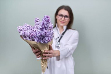 Kadın doktorun ellerinde bir demet leylak çiçeği.