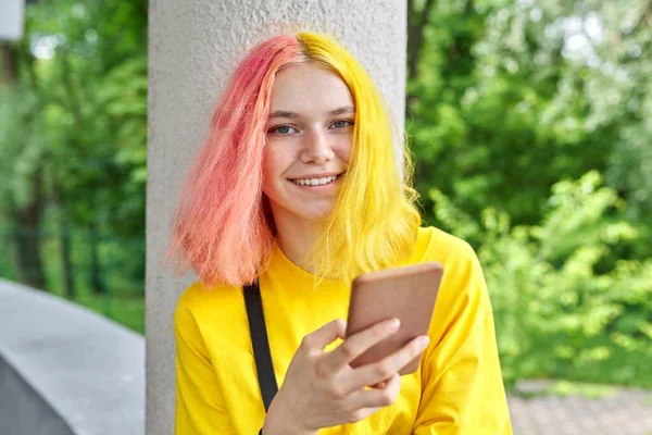 Chica adolescente de moda con el pelo teñido de color con un teléfono inteligente al aire libre. — Foto de Stock