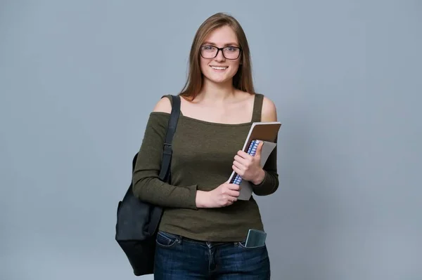 Retrato de estudiante universitario sonriente en gafas con mochila sobre fondo gris —  Fotos de Stock