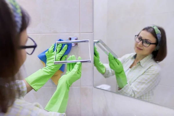 Уборка ванной комнаты, женщина в перчатках с тряпкой, стирка и полировка плитки стены — стоковое фото