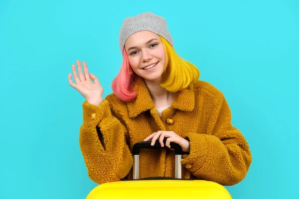 Teenager žena v klobouku kožich kabát s kufrem na modrém tyrkysovém pozadí — Stock fotografie