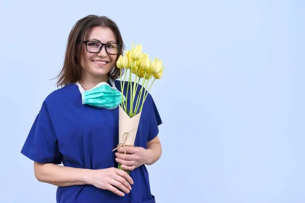 Sorrindo mulher madura médico enfermeira com buquê de flores, dia de trabalhador médico, espaço de cópia — Fotografia de Stock